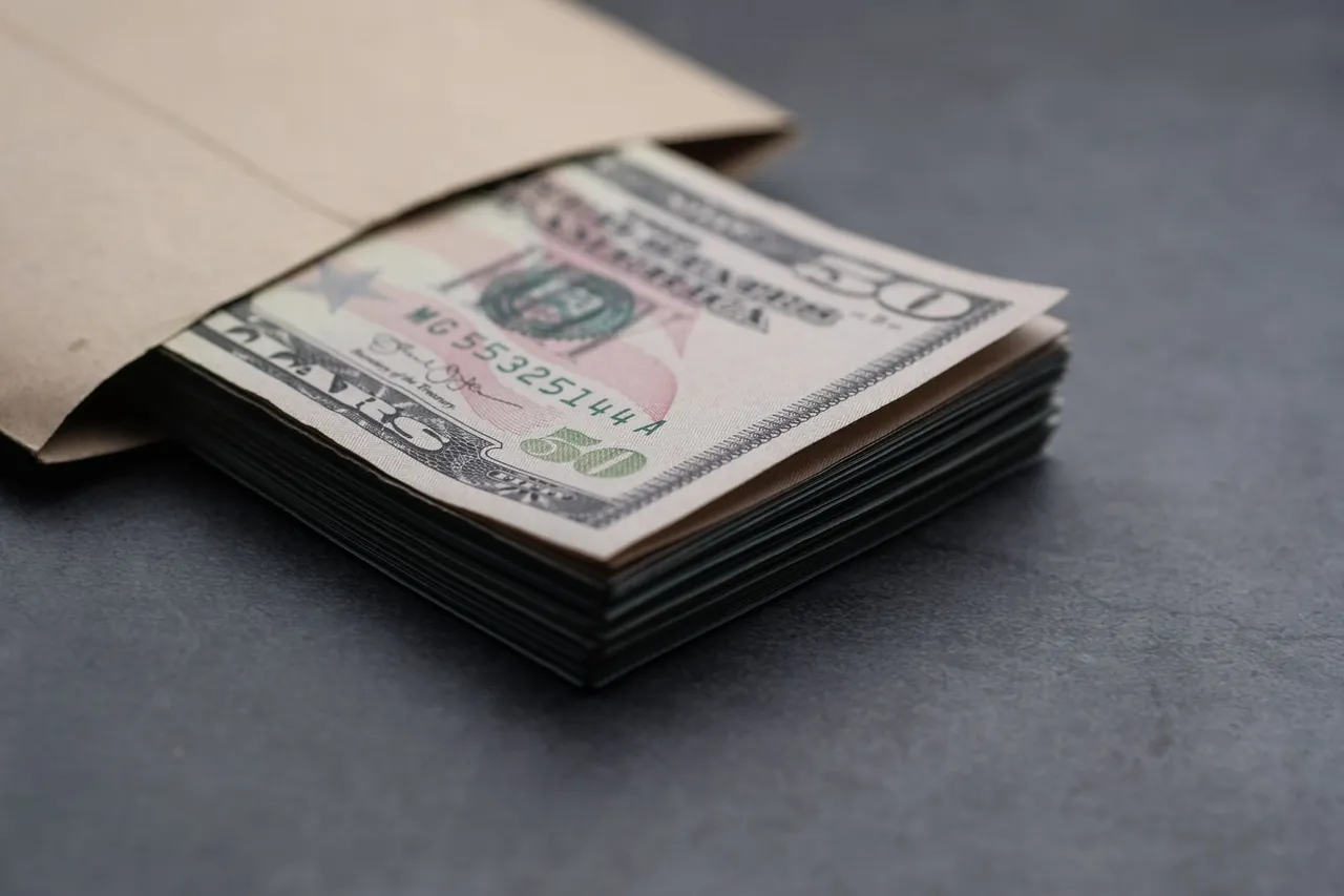 Close-up of US fifty dollar bills partially enclosed in a brown envelope, symbolizing finances.
