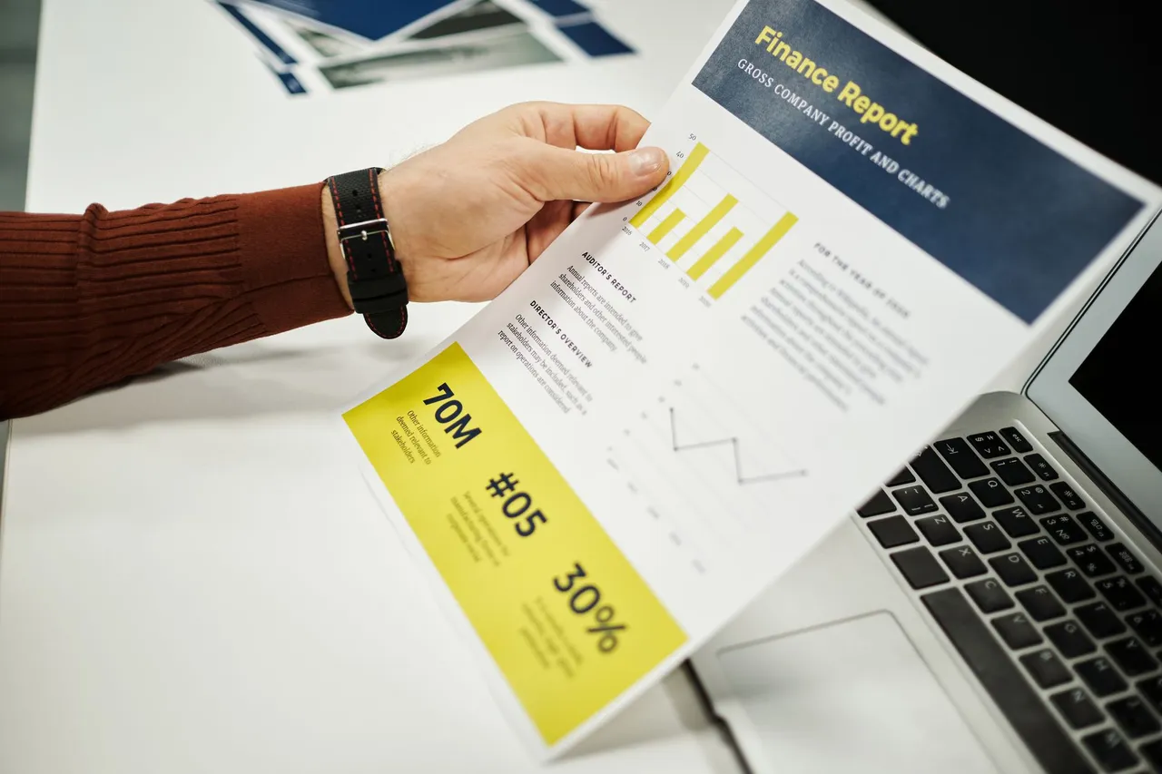 Person reviewing a finance report with graphs at a desk.
