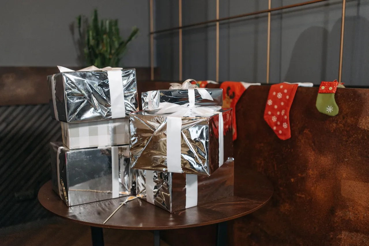 Wrapped gift boxes and festive stockings on a wooden table.