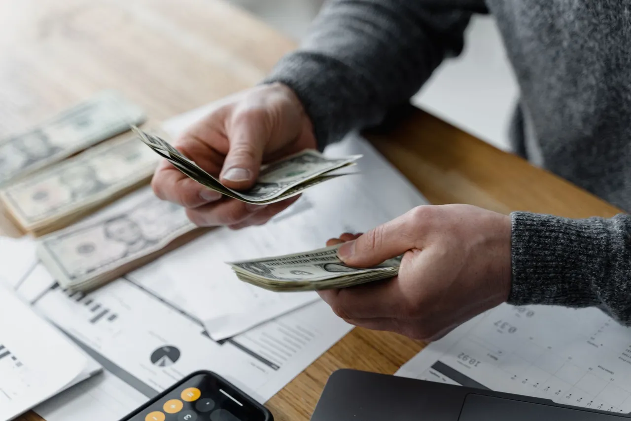 Hands handling cash and calculator for budget planning. Modern financial scene.