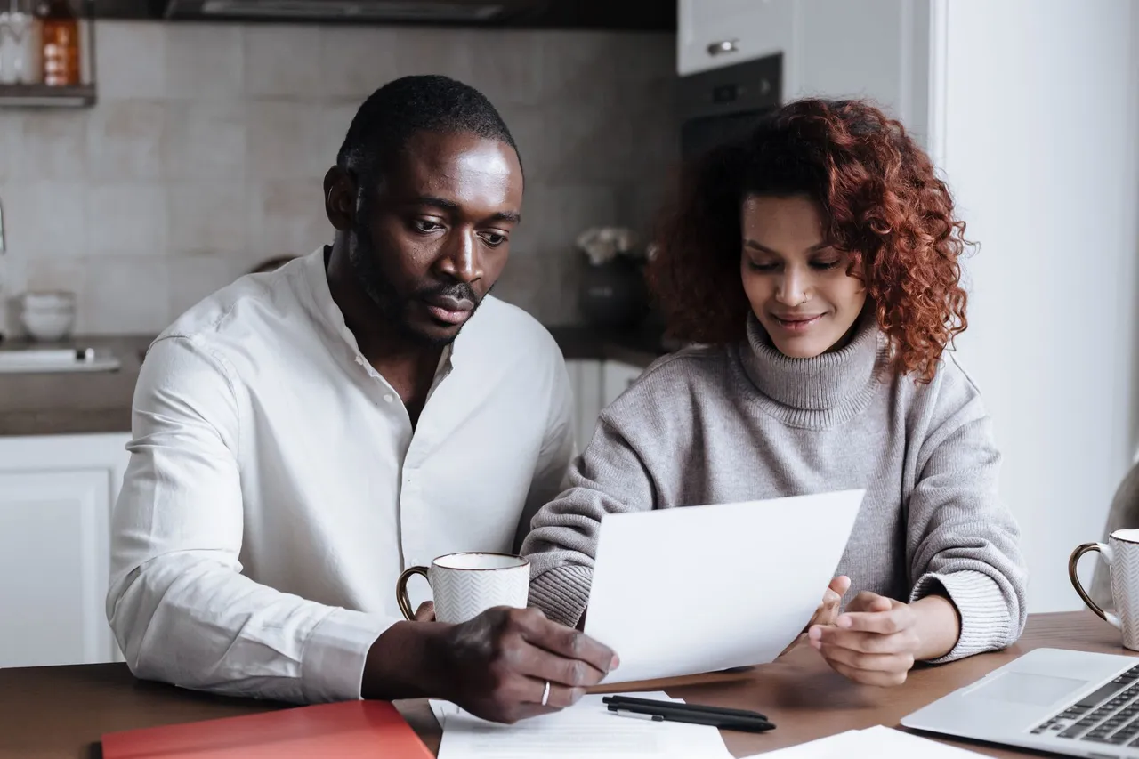A couple reviewing paperwork together at a kitchen table.