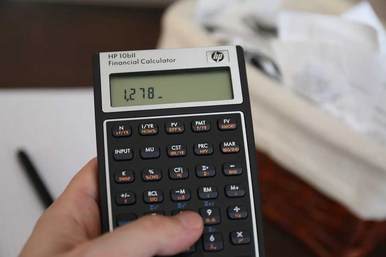 Cash, bills, and a calculator on a desk for working out monthly expenses.